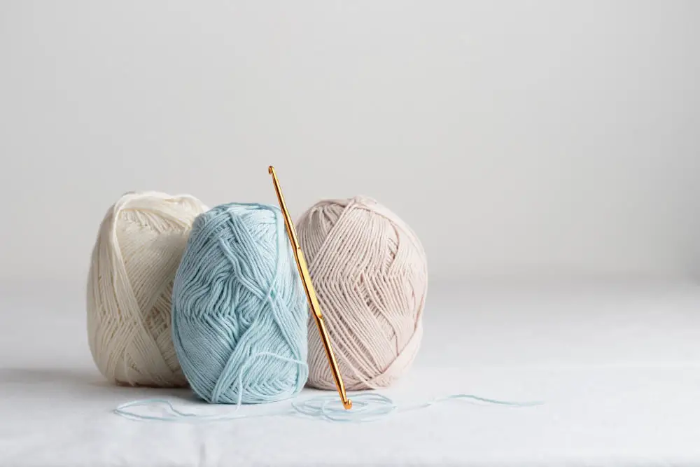 Crochet hook and balls of cotton yarn